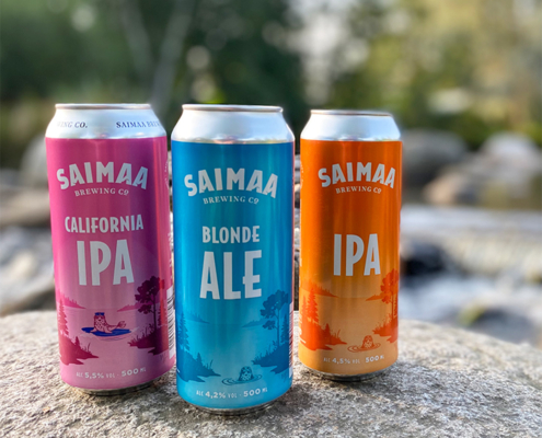 Kuvassa Saimaa Brewing Companyn uudistuneita oluttölkkipakkauksia kesäisen jokikuohun äärellä.